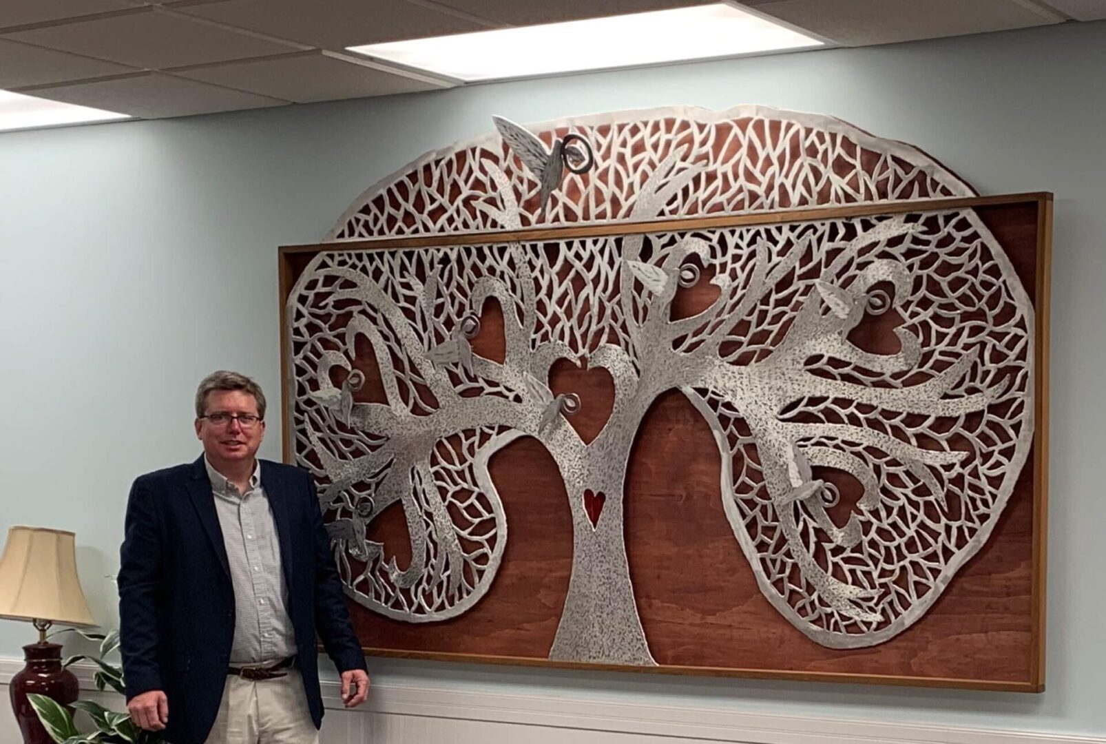 A man standing in front of a wooden tree.