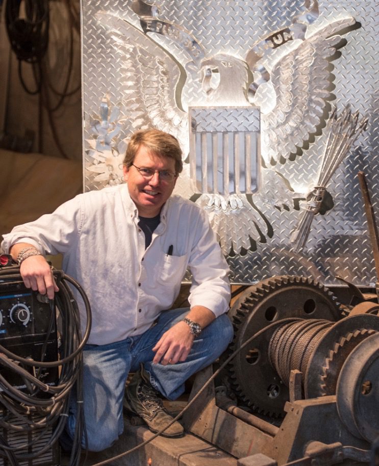 A man sitting on the ground next to some metal