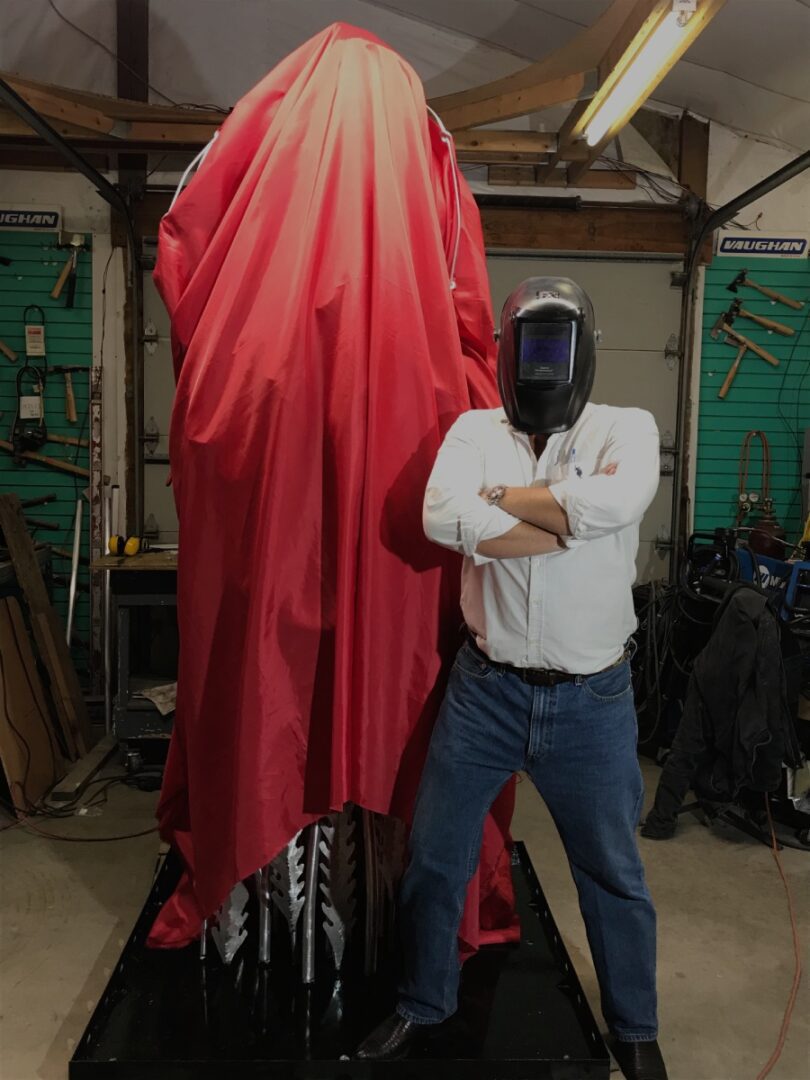 A man standing next to a large red statue.