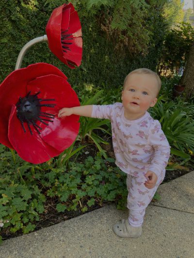 A baby in pajamas holding onto a giant flower.