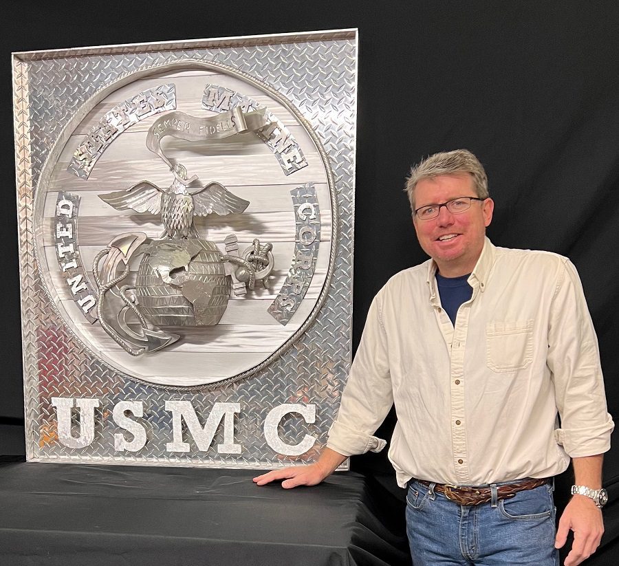 A man standing next to a large metal sign.