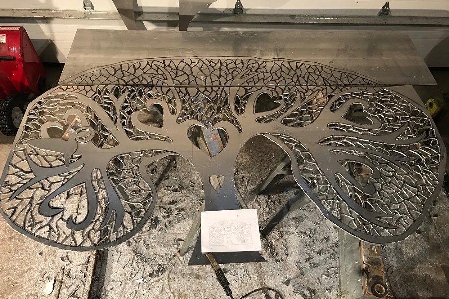 A metal sculpture of trees with leaves on it.