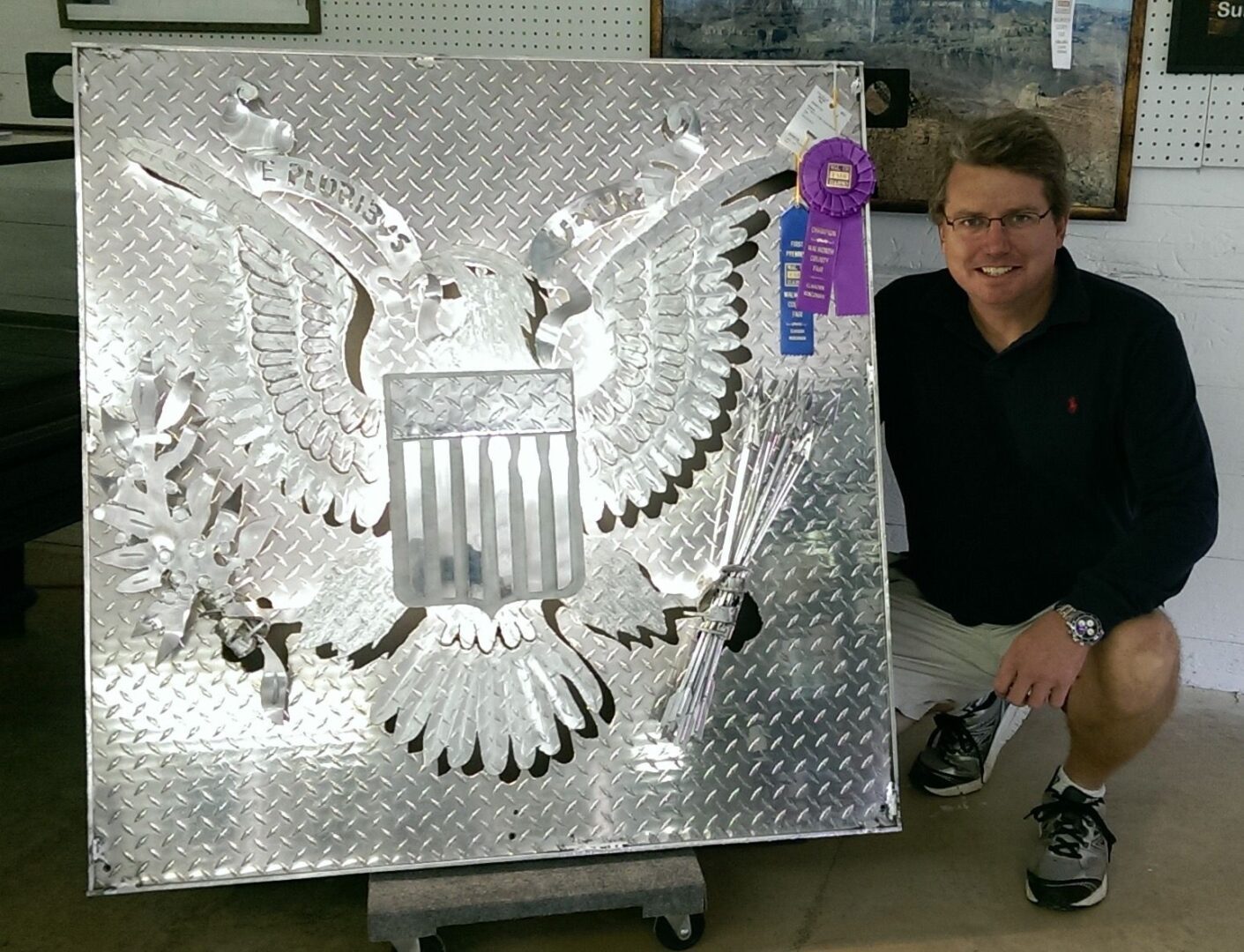 A man sitting next to a metal sculpture.