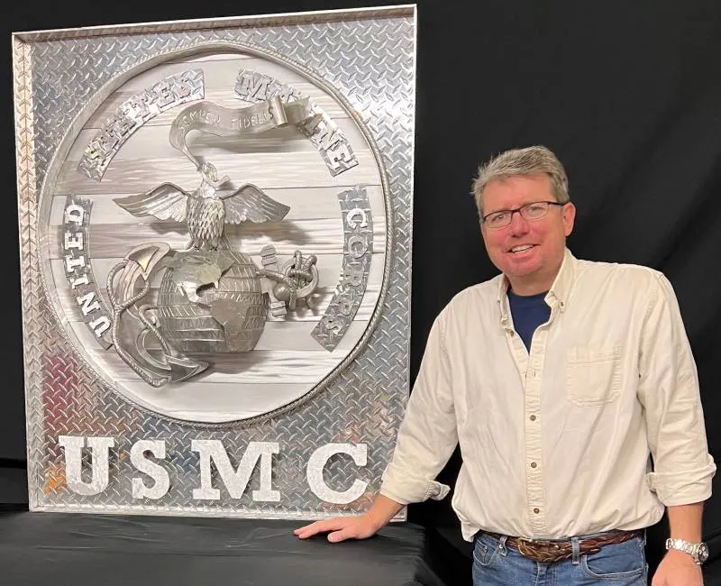 A man standing next to a large metal sign.