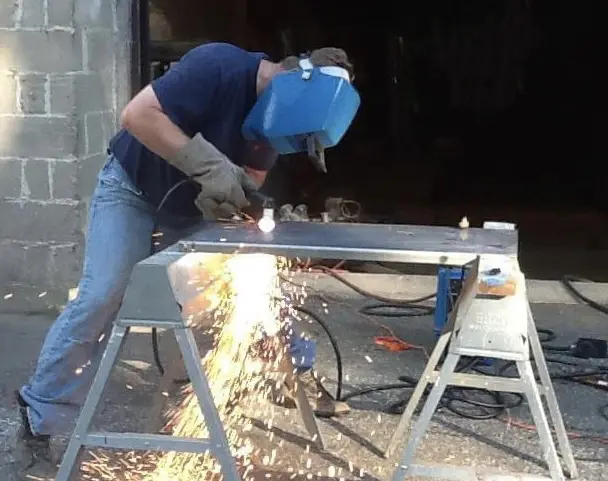 A man welding metal with a mask on.